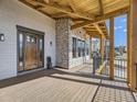 Covered porch with stone accents and a wooden deck, offering views of the neighborhood at 3534 Running Deer Dr, Castle Rock, CO 80109