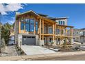 Modern farmhouse style home with wood siding, stone accents and a three-car garage at 3534 Running Deer Dr, Castle Rock, CO 80109