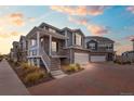 Two-story townhome with gray siding, brick accents, and a covered porch at 21844 E 44Th Dr, Aurora, CO 80019