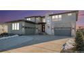 Modern two-story home with a three-car garage and a paved driveway at dusk at 3564 Doubletrack Ln, Castle Rock, CO 80108