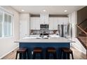 Modern kitchen with white cabinets, blue island, and stainless steel appliances at 8835 Meade St, Westminster, CO 80031