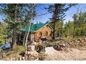 Rustic mountain cabin with a green roof and stone accents at 80 Outlook Dr, Golden, CO 80403