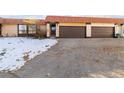 Tan exterior home with brown double garage doors and snow-covered landscaping at 1453 S Salem Way, Aurora, CO 80012