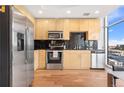 Modern kitchen with stainless steel appliances, black tile backsplash, and light wood cabinets at 1700 Bassett St # 1319, Denver, CO 80202