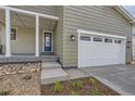 Front entry and attached two-car garage with gray siding and landscaping at 11076 Star Fall St, Littleton, CO 80125