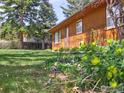 Side view of a wood-sided house with green lawn and blooming flowers at 913 Utica Ave, Boulder, CO 80304