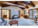 Spacious living room featuring exposed wooden beams, a cozy sitting area, and access to a deck at 124 Deer Trail Cir, Boulder, CO 80302