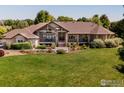 Ranch-style home with a large front yard, expansive driveway and mature trees at 385 Baxter Farm Ln, Erie, CO 80516