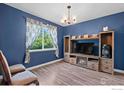 Living room with blue walls, hardwood floors and a media center at 11043 Nome St, Commerce City, CO 80640