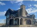 Under construction, two-story home with stone and wood exterior, solar panels, and covered porch at 917 Latigo Loop, Lafayette, CO 80026