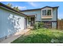 Side view of a light blue house with a door and landscaping at 1900 Logan St, Longmont, CO 80501