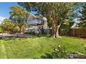 Charming two-story home with a large tree in front and a spacious lawn at 1110 Hover St, Longmont, CO 80501