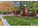 Two-story red house with a deck, white picket fence, and beautiful landscaping at 1282 Elder Ave, Boulder, CO 80304