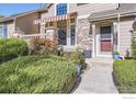 Townhome entrance with red door, landscaping, and striped awning at 6220 Salvia St, Arvada, CO 80403