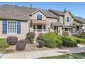 Tan two-story townhome with red door, landscaping, and striped awning at 6220 Salvia St, Arvada, CO 80403