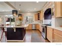 Kitchen with an island, wood cabinets, and a patterned backsplash at 185 Pipit Lake Way, Erie, CO 80516