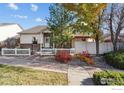 Inviting exterior with a landscaped yard, white picket fence and a brick walkway at 3123 Concord Way, Longmont, CO 80503