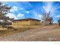 Side view of the house showcasing a gravel driveway and fenced yard at 3520 W County Road 8, Berthoud, CO 80513