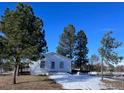 White house with mature trees and a partially snow-covered yard at 525 Dale Ct, Elizabeth, CO 80107