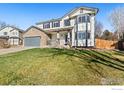 Two-story home with stone accents, front porch, and green lawn at 1624 Cedarwood Dr, Longmont, CO 80504