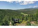 Stunning aerial view of a mountain home surrounded by lush greenery at 7142 Lynx Lair Rd, Evergreen, CO 80439