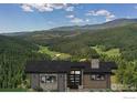 Front exterior view of a modern home nestled in a mountain landscape at 7142 Lynx Lair Rd, Evergreen, CO 80439
