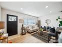 Bright living room with hardwood floors, stylish furniture, and large window at 1101 Village Dr, Fort Lupton, CO 80621