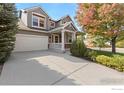 Two-story house with gray siding, a white garage door and a covered porch at 2429 Tyrrhenian Dr, Longmont, CO 80504