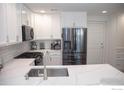 Modern kitchen with white cabinets, quartz countertops, and stainless steel appliances at 9841 E 56Th Pl, Denver, CO 80238