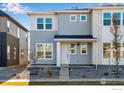 Two-story townhome with gray siding, stone accents, and a landscaped front yard at 1773 Mount Meeker Ave, Berthoud, CO 80513