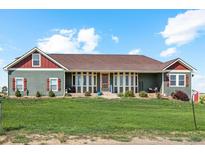 Ranch style home with green siding, red accents, and a large yard at 54333 E County Road 26, Strasburg, CO 80136