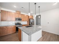 Modern kitchen with light wood cabinets and granite island at 6153 N Ceylon St # 303, Denver, CO 80249