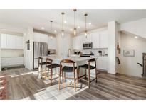 Modern kitchen with island, stainless steel appliances, and white cabinetry at 810 Compass Dr, Erie, CO 80516