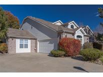 Charming two-story home with a gray and brick exterior, white garage door, and landscaped front yard at 877 Home Farm Ave, Westminster, CO 80234