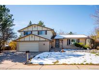 Two-story house with a beige brick exterior, attached garage, and a snow-covered front yard at 7420 W Caley Dr, Littleton, CO 80123