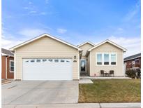 Beige house with a two-car garage and landscaping at 6280 Indian Paintbrush St, Frederick, CO 80530