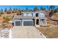 Two-story house with gray siding, two-car garage, and a landscaped yard at 4285 Mohawk Dr, Larkspur, CO 80118