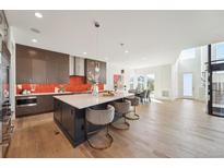 Modern kitchen with island, stainless steel appliances, and orange backsplash at 9811 E 63Rd Ave, Denver, CO 80238