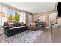 Bright living room features hardwood floors, comfy seating, and a view of the backyard at 4711 S Clarkson St, Englewood, CO 80113