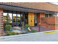 Condominium building's entrance with unique gold doors and landscaping at 4570 E Yale Ave # 706, Denver, CO 80222