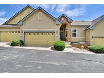 Tan two-story townhome with two-car garage, landscaping, and a paved driveway at 6678 S Shawnee Ct, Aurora, CO 80016