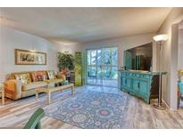 Living room with wood-look flooring, access to patio and large windows at 13609 E Cornell Ave # 107, Aurora, CO 80014