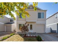 Tan two-story house with gray accents, landscaping, and a paved driveway at 18636 E 45Th Pl, Denver, CO 80249