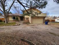 House exterior featuring a two-car garage and well-maintained landscaping at 8025 S Cody St, Littleton, CO 80128