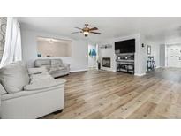 Bright living room with hardwood floors, fireplace, and large TV at 15386 E 101St Pl, Commerce City, CO 80022