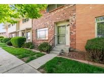 Brick townhome exterior with a manicured lawn and walkway at 9079 E Nassau Ave, Denver, CO 80237