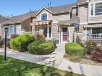 Tan two-story townhome with red door, landscaping, and walkway at 6220 Salvia St, Arvada, CO 80403