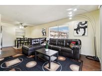 Living room features a leather sectional sofa, coffee table, and hardwood floors at 10211 Ura Ln # 8-207, Thornton, CO 80260