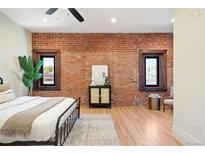 Spacious bedroom with exposed brick wall, hardwood floors, and large windows at 1763 N Williams St # 202, Denver, CO 80218