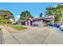 Red and gray ranch house with carport and landscaped yard at 7050 Alan Dr, Denver, CO 80221